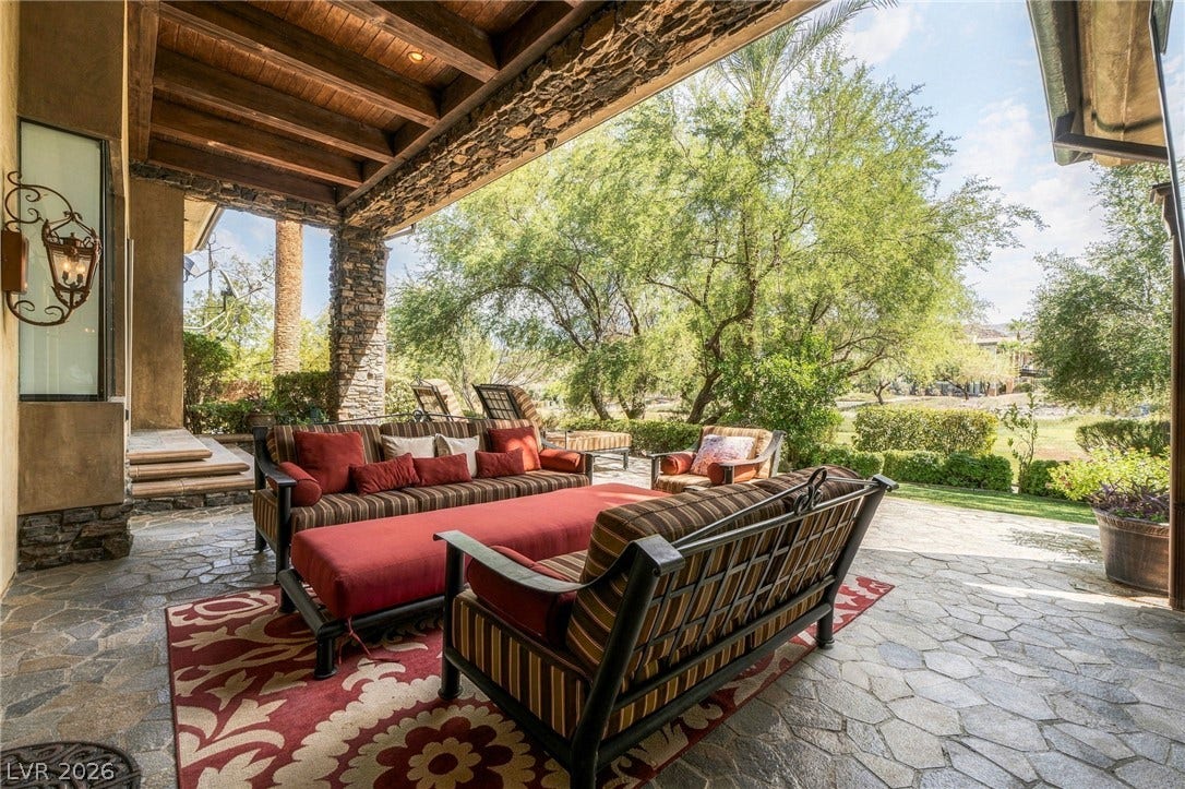 1513 Foothills Village Drive, Henderson, NV 89012 Rich wood ceilings and stone pillars frame a flagstone terrace overlooking lush, mature landscaping.
