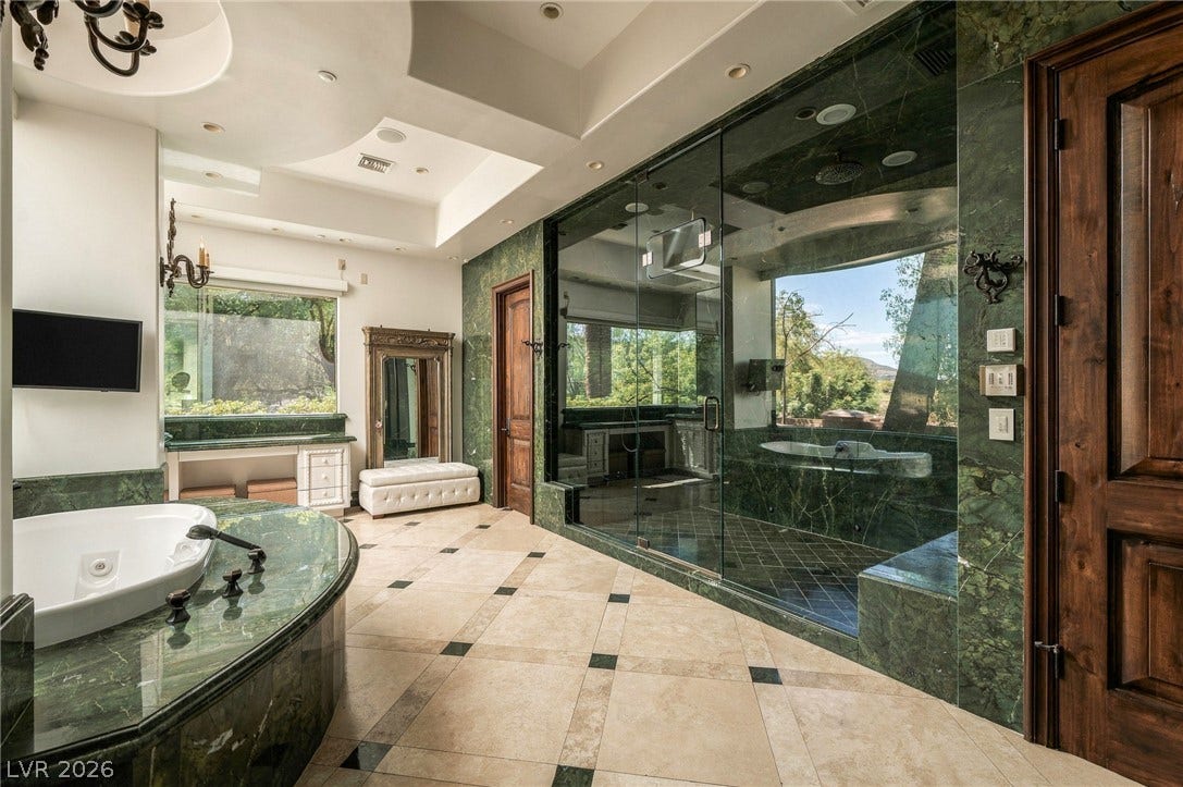 1513 Foothills Village Drive, Henderson, NV 89012 Luxurious stone finishes and a massive glass-enclosed shower define this spa-like bathroom.