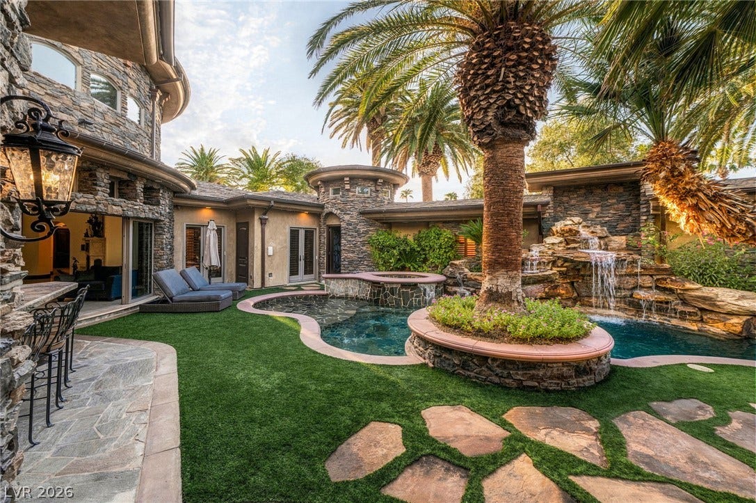 1513 Foothills Village Drive, Henderson, NV 89012 Natural stone masonry and towering palms frame a custom pool with an integrated rock waterfall.