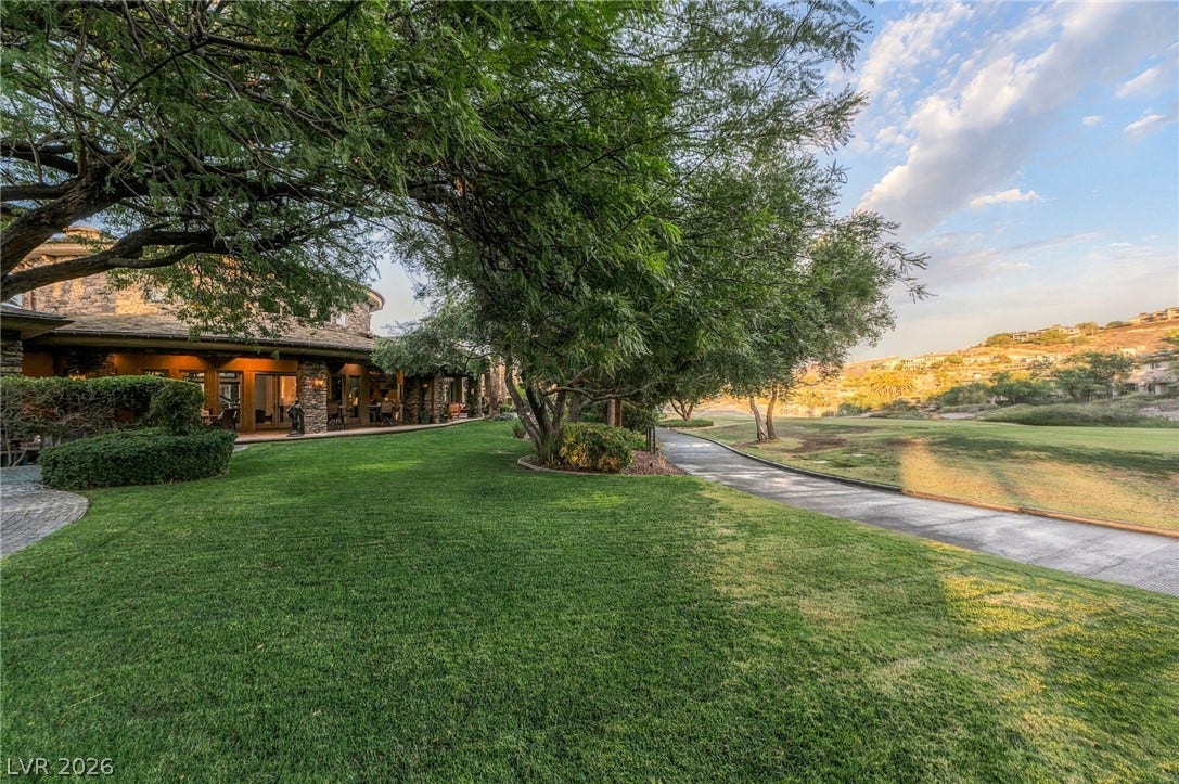 1513 Foothills Village Drive, Henderson, NV 89012 Mature trees shade a manicured lawn alongside a paved path bordering the golf course.