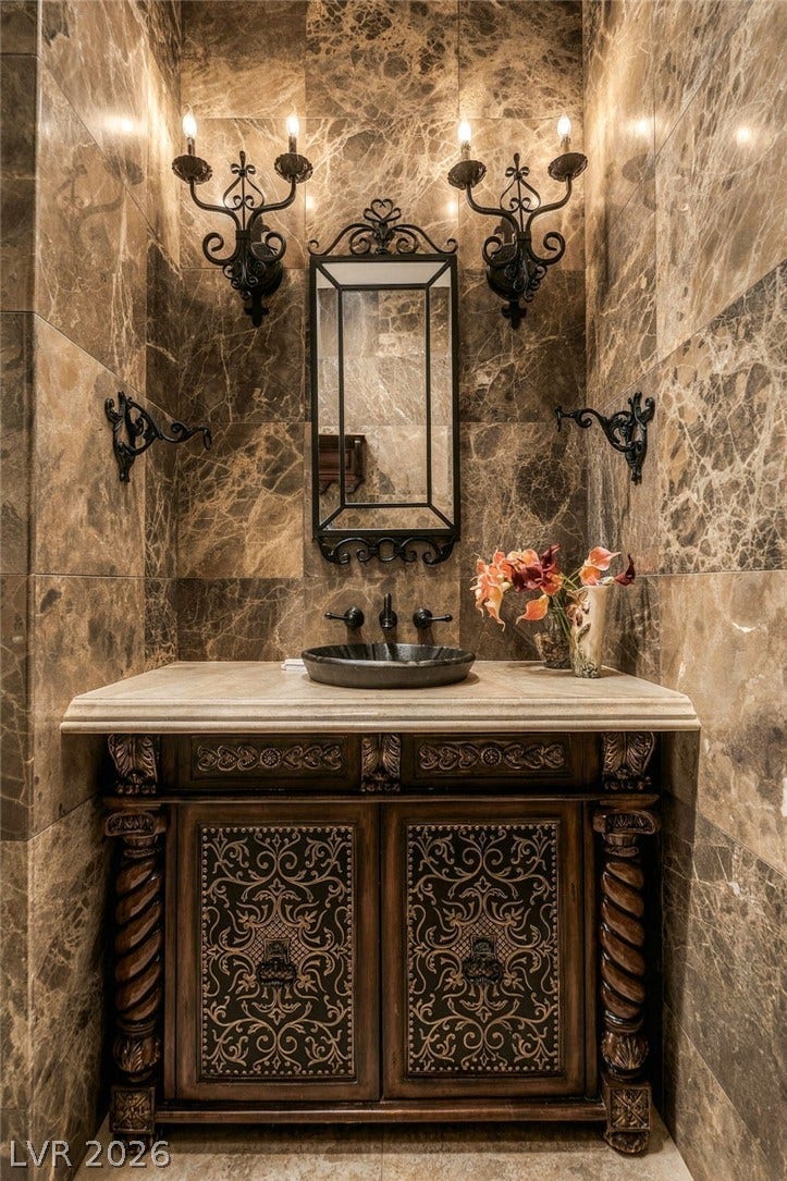 1513 Foothills Village Drive, Henderson, NV 89012 Ornate stone tile surrounds a classic carved vanity and matching wrought iron fixtures.