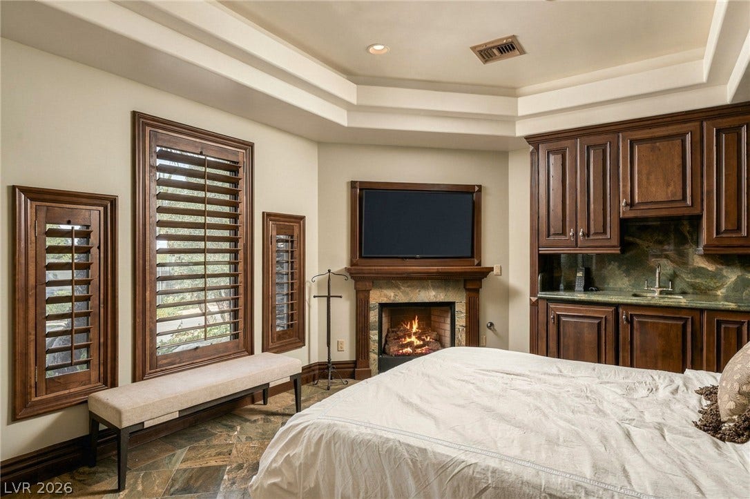 1513 Foothills Village Drive, Henderson, NV 89012 Warm wood details, a cozy fireplace, and natural stone flooring elevate this comfortable bedroom sanctuary.