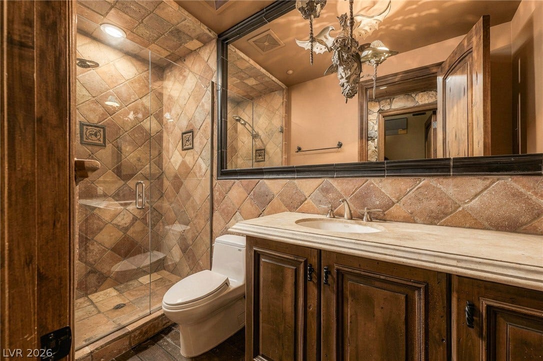 1513 Foothills Village Drive, Henderson, NV 89012 Richly textured stone tile and warm wood cabinetry define this inviting bathroom space.