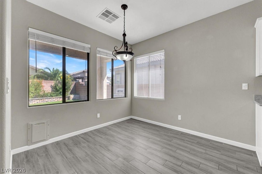 Sunlight streams through generous windows highlighting the stylish plank flooring.