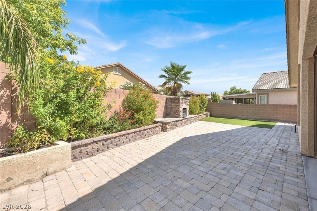 An inviting stone-paved patio offers a quiet space alongside a built-in outdoor stone fireplace.