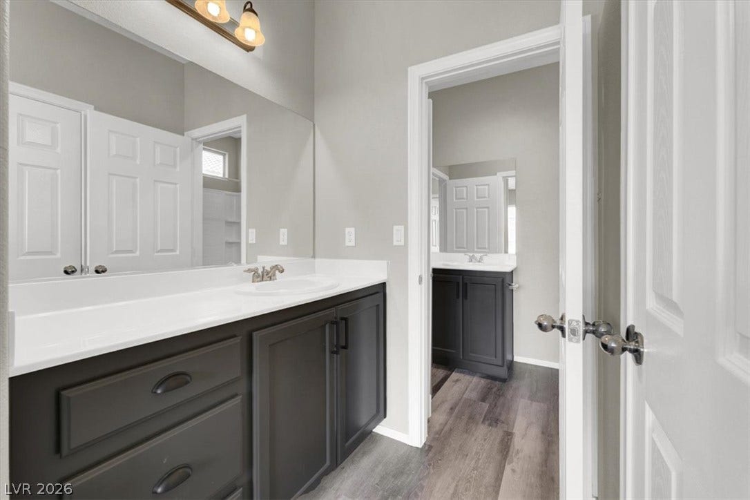 Crisp white countertops contrast beautifully with dark cabinetry over wood-patterned flooring.