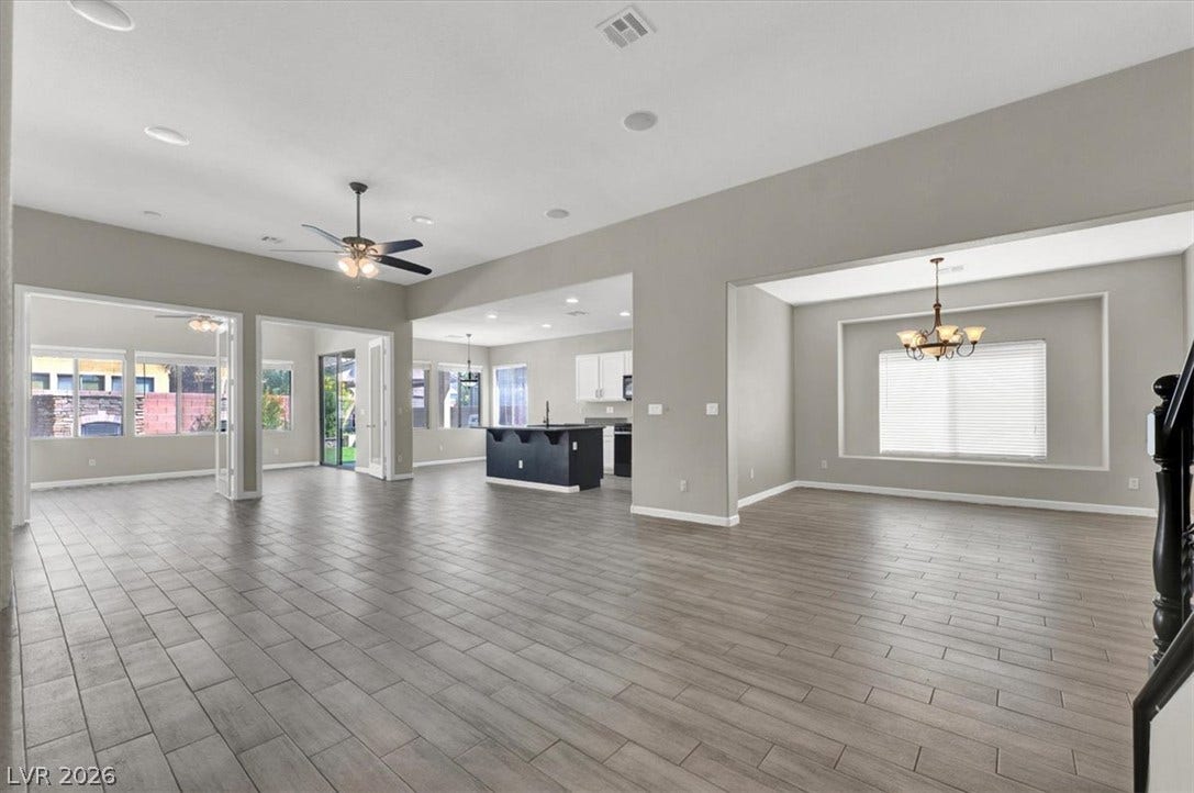 Gleaming plank tile floors stretch throughout a spacious, open-concept layout connecting multiple living areas.