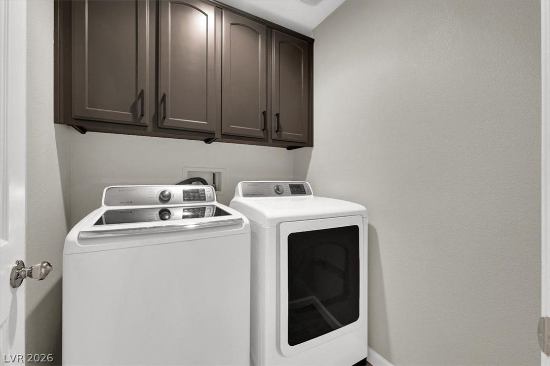 Dark upper cabinetry provides useful storage space directly above the laundry appliances.