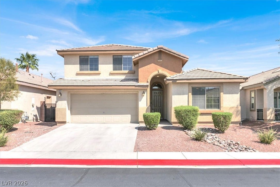 Desert landscaping and a paved driveway complement this two-story stucco exterior design.
