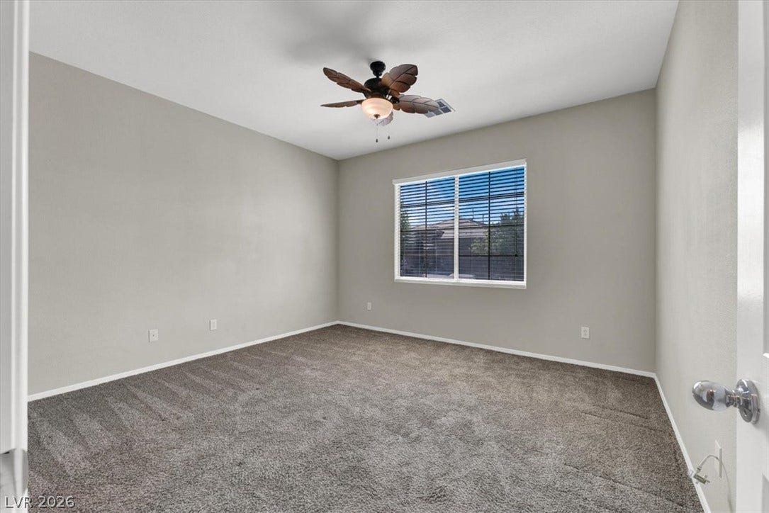 Plush carpeting and a large window define this versatile secondary bedroom space.