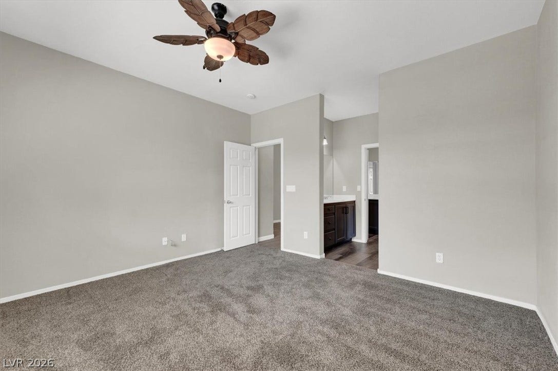 Plush carpeting and an open layout connect the primary bedroom to the adjacent bathroom.