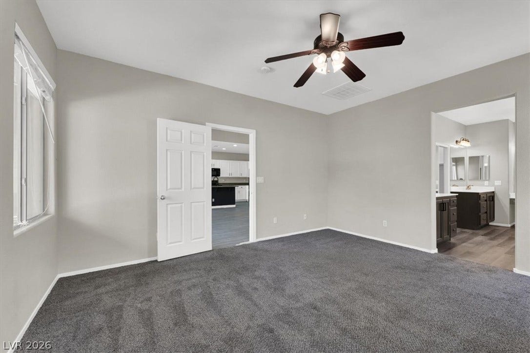 An open doorway connects this carpeted bedroom directly to the neighboring spaces.