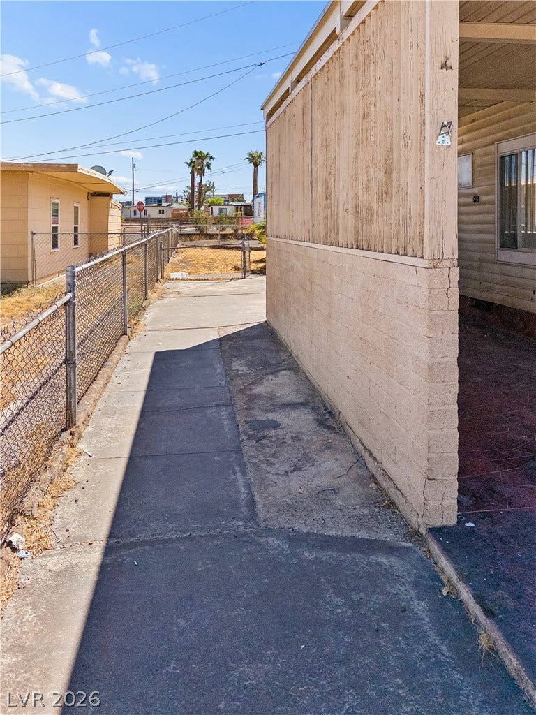 107 W Victory Road, Henderson, NV 89015 A concrete walkway runs along the side of the home under sunny desert skies.