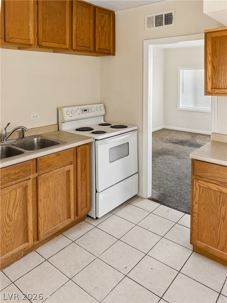 107 W Victory Road, Henderson, NV 89015 Tiled flooring and classic wooden cabinetry define this functional kitchen space.