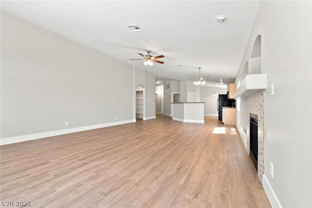 6059 Camden Cove Street, North Las Vegas, NV 89081 Warm wood-look flooring and a cozy fireplace anchor this open-concept main living space.