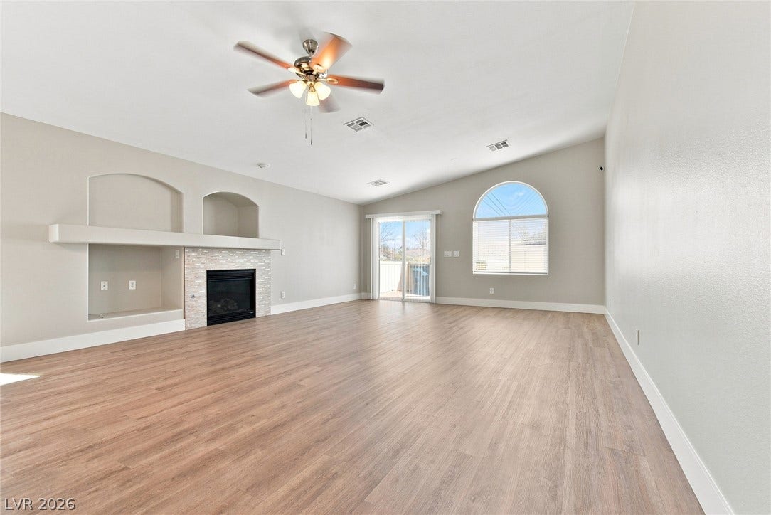 6059 Camden Cove Street, North Las Vegas, NV 89081 Vaulted ceilings and wood-style flooring elevate this airy living space complete with a fireplace.
