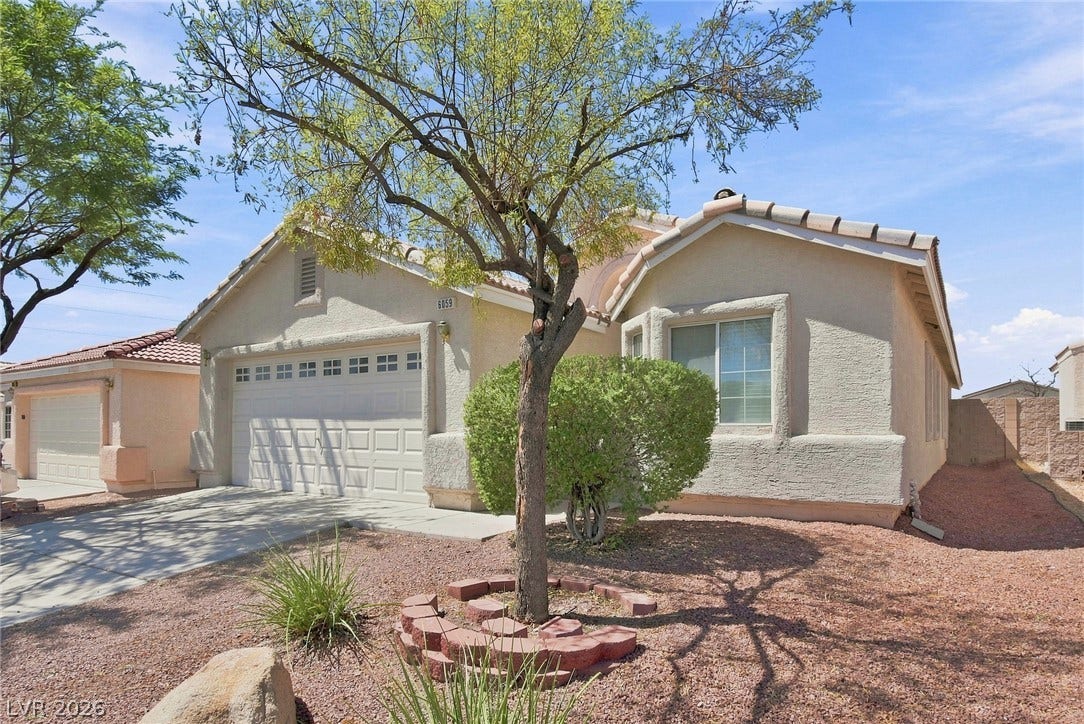 6059 Camden Cove Street, North Las Vegas, NV 89081 Desert landscaping and a stucco exterior frame this single-story home with an attached garage.