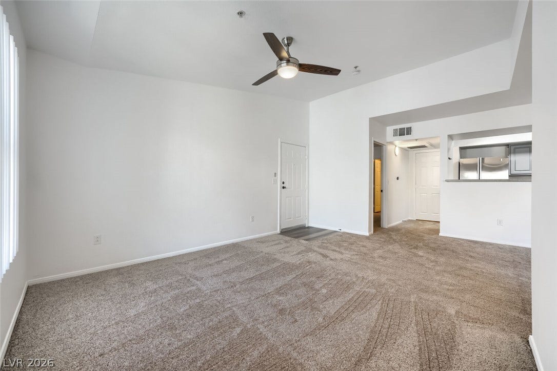 6955 N Durango Drive, #3102, Las Vegas, NV 89149 Spacious living room with high ceilings and new carpet, offering an open flow to the kitchen and convenient access to the guest bedroom and adjoining guest bath.