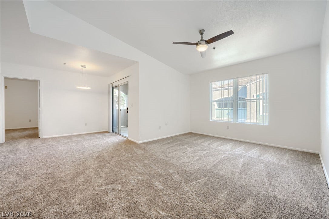 6955 N Durango Drive, #3102, Las Vegas, NV 89149 An open living and dining area features plush new carpeting, new paint, and sliding glass door access to balcony.