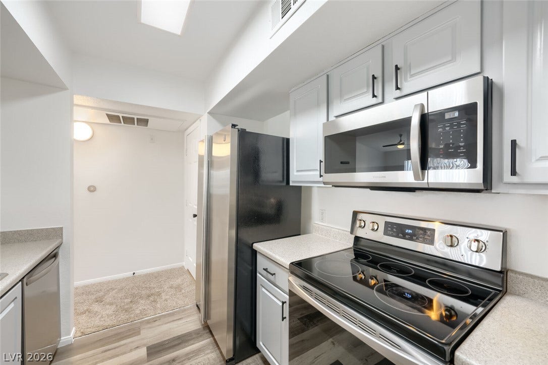 6955 N Durango Drive, #3102, Las Vegas, NV 89149 Bright, updated kitchen featuring newer cabinetry, LVP flooring and stainless-steel appliances, opening to the dining and living areas with easy access to the balcony.