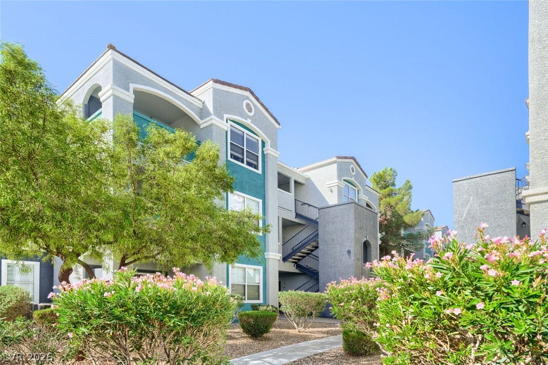 6955 N Durango Drive, #3102, Las Vegas, NV 89149 Front courtyard entry with lush landscaping frames the exterior of this modern multi-level residential building.