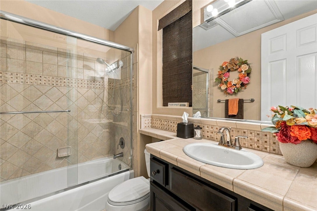 12056 Royal Dolnoch Court, Las Vegas, NV 89141 Tiled accents and a glass-enclosed tub shower highlight this comfortable secondary bathroom.