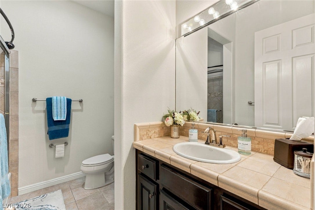12056 Royal Dolnoch Court, Las Vegas, NV 89141 Tile countertops and dark wood cabinetry define this functional guest bathroom.