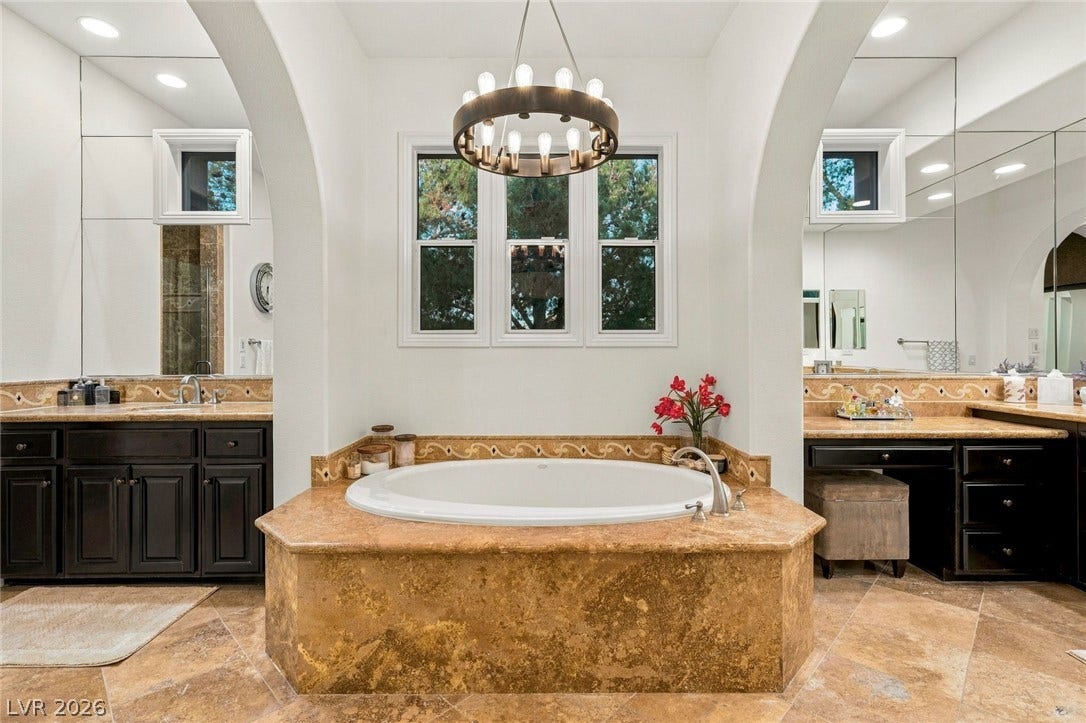12056 Royal Dolnoch Court, Las Vegas, NV 89141 Arched entryways frame a central soaking tub and double vanities under high ceilings.
