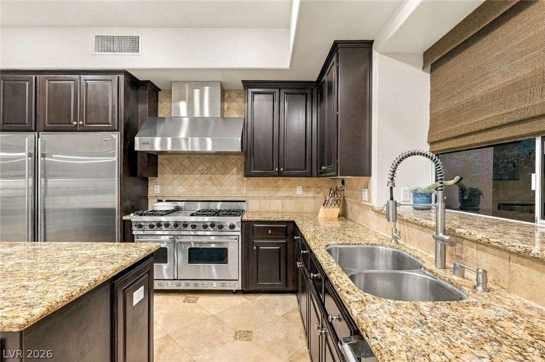 12056 Royal Dolnoch Court, Las Vegas, NV 89141 Rich dark cabinetry pairs beautifully with expansive granite countertops and professional-grade stainless steel appliances.
