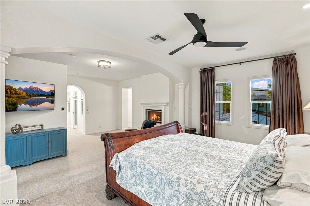 12056 Royal Dolnoch Court, Las Vegas, NV 89141 An open bedroom layout connects seamlessly to an adjacent sitting area anchored by a fireplace.