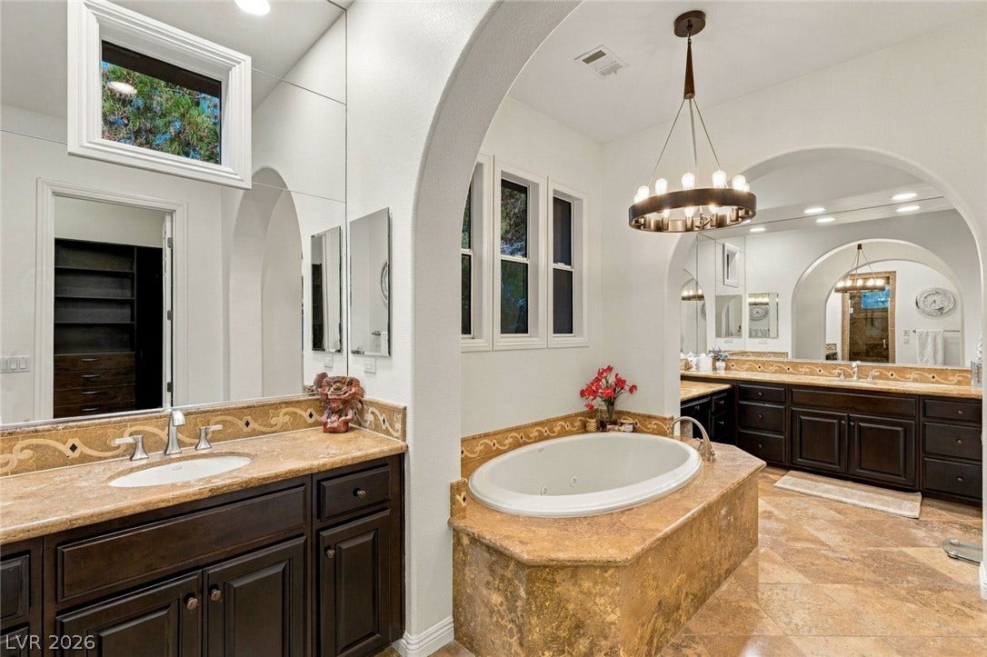 12056 Royal Dolnoch Court, Las Vegas, NV 89141 An elegant arched entryway frames a luxurious soaking tub and matching stone-topped vanities.