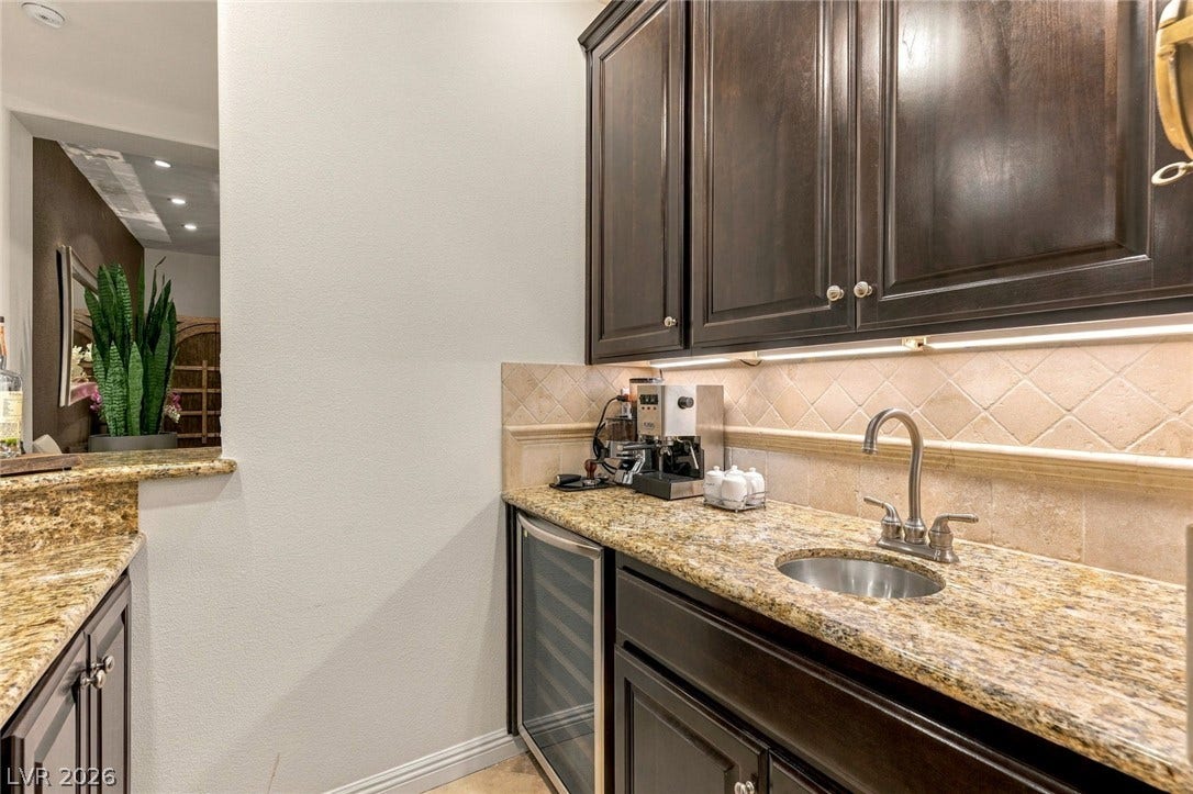 12056 Royal Dolnoch Court, Las Vegas, NV 89141 Rich dark wood cabinets and stone countertops accent this elegant home bar area.