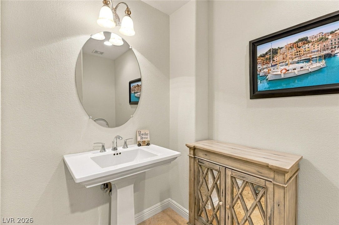 12056 Royal Dolnoch Court, Las Vegas, NV 89141 A classic pedestal sink sits beneath an oval mirror in this clean powder room.