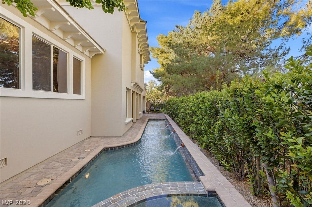 12056 Royal Dolnoch Court, Las Vegas, NV 89141 Manicured hedges frame a sleek water feature alongside a paved walkway.