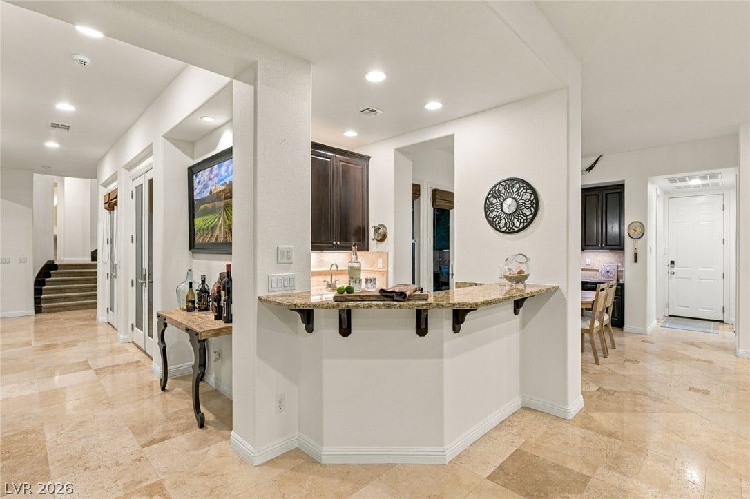 12056 Royal Dolnoch Court, Las Vegas, NV 89141 Polished tile flooring and arched architectural details frame this wet bar and welcoming foyer.