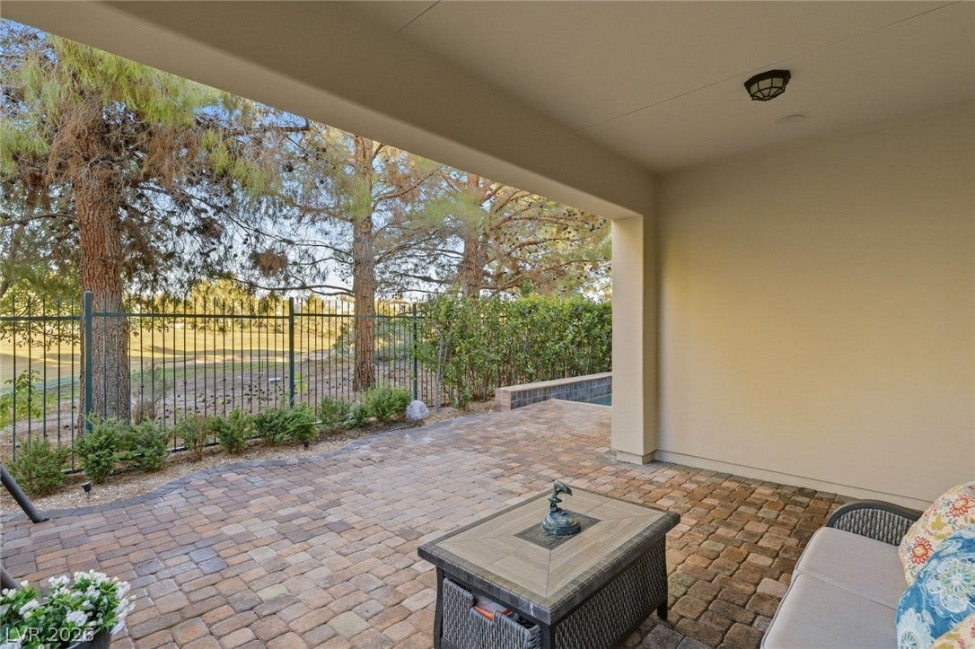12056 Royal Dolnoch Court, Las Vegas, NV 89141 A sheltered brick patio looks out over a fenced yard with mature shade trees.