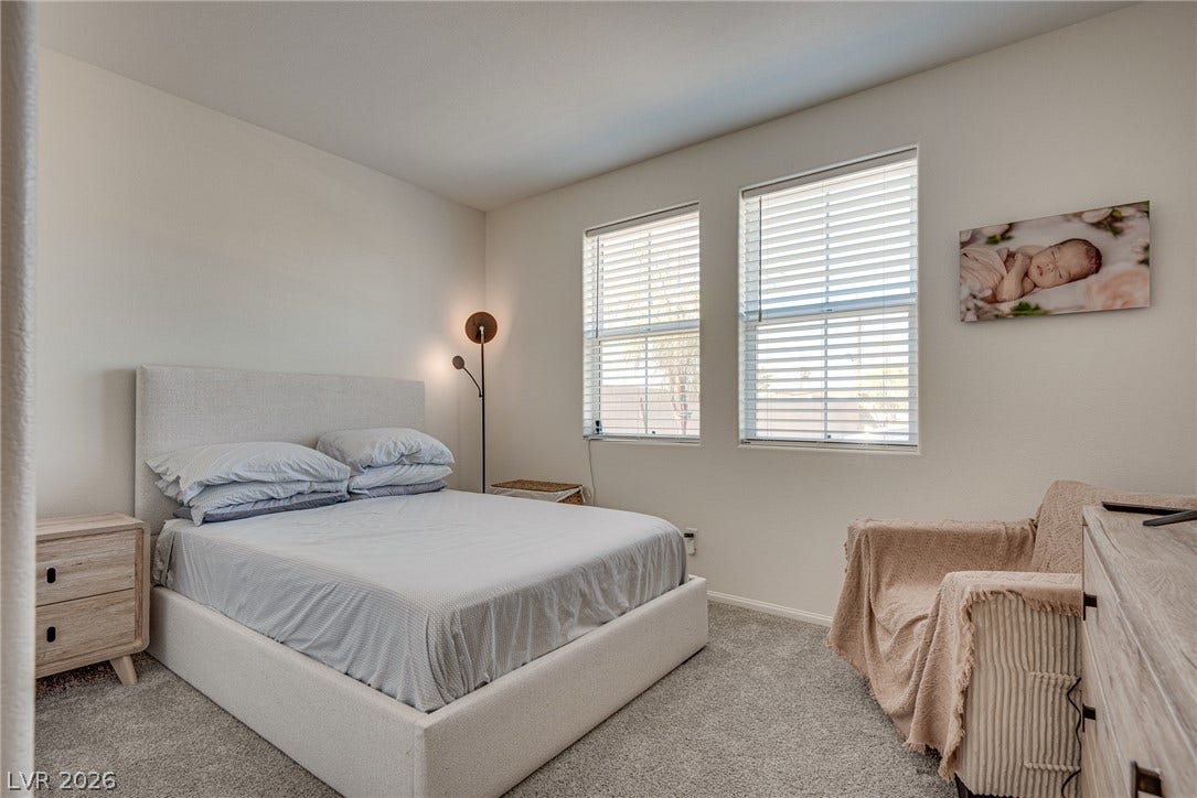 Plentiful natural light streams through dual windows in this comfortable carpeted bedroom.