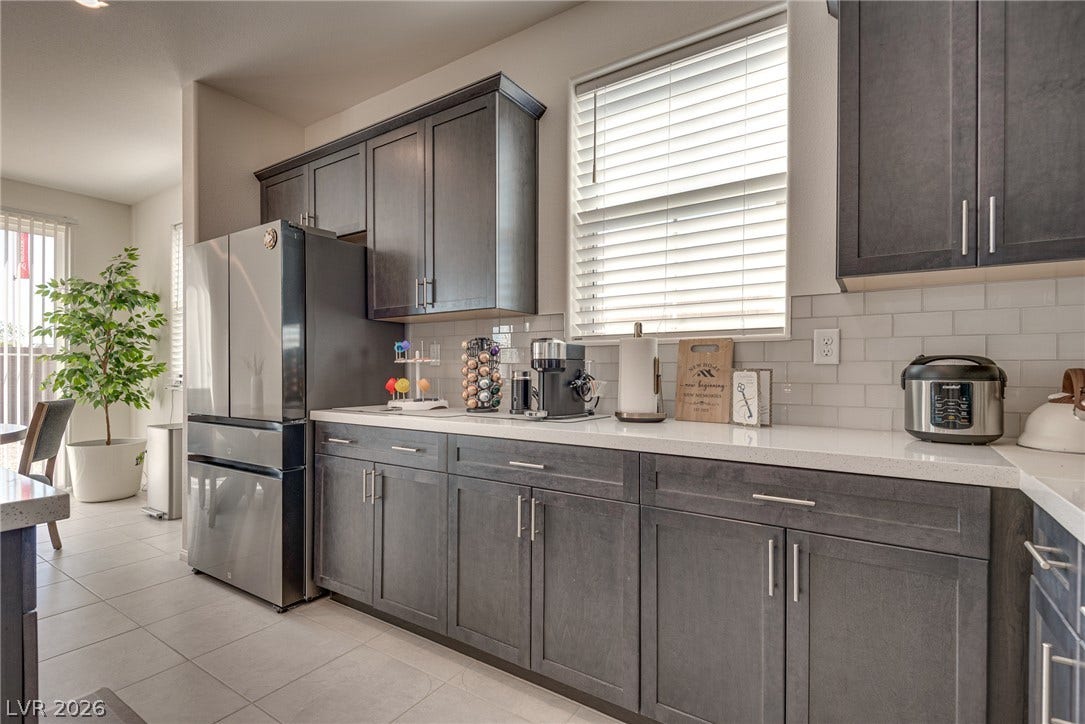 Dark cabinetry and quartz countertops define this modern kitchen with tile flooring.