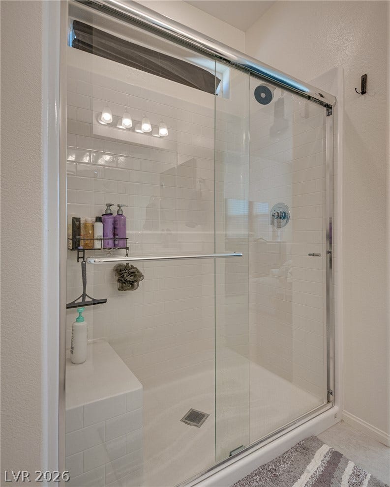 A glass-enclosed walk-in shower features classic subway tile and a convenient built-in bench.
