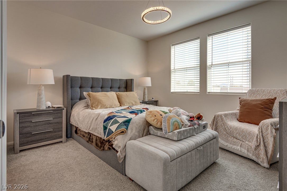 Natural light pours through dual windows onto plush carpeting in this serene bedroom.