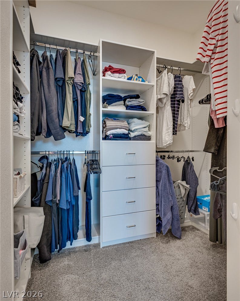 Organized custom shelving and integrated drawers maximize storage space within this walk-in closet.