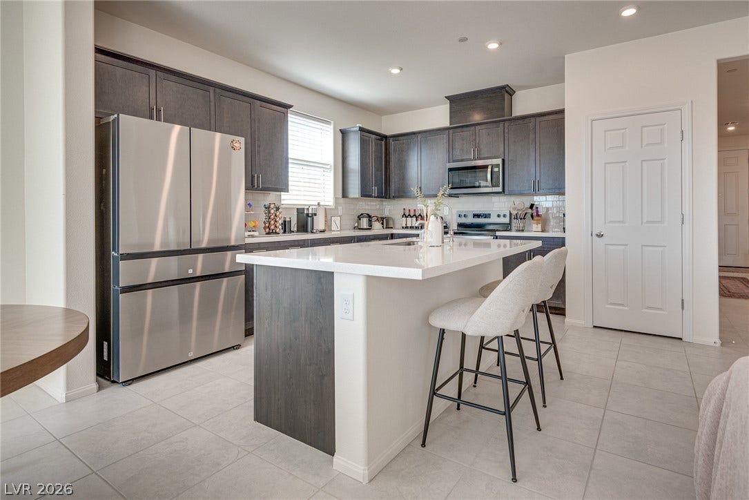 Dark cabinetry beautifully contrasts with a white center island and light tile flooring.