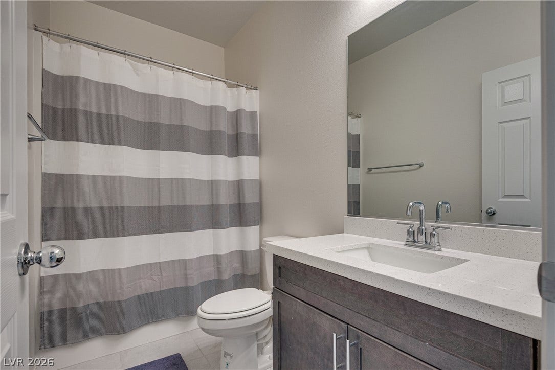 An elegant single vanity sits beneath a large mirror in this modern full bathroom.