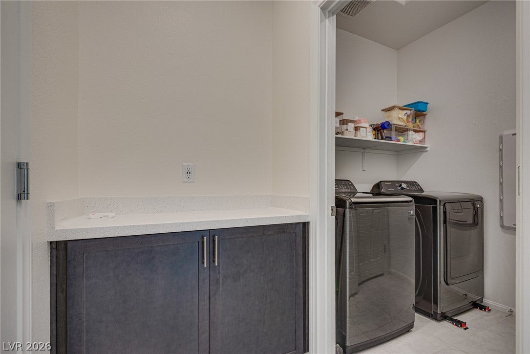 An organized laundry area includes modern storage cabinets and built-in folding space.