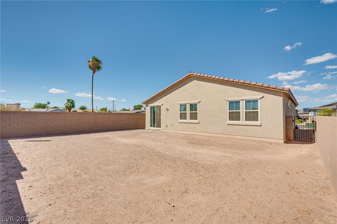 An expansive gravel yard enclosed by a block privacy wall offers endless personalization potential.
