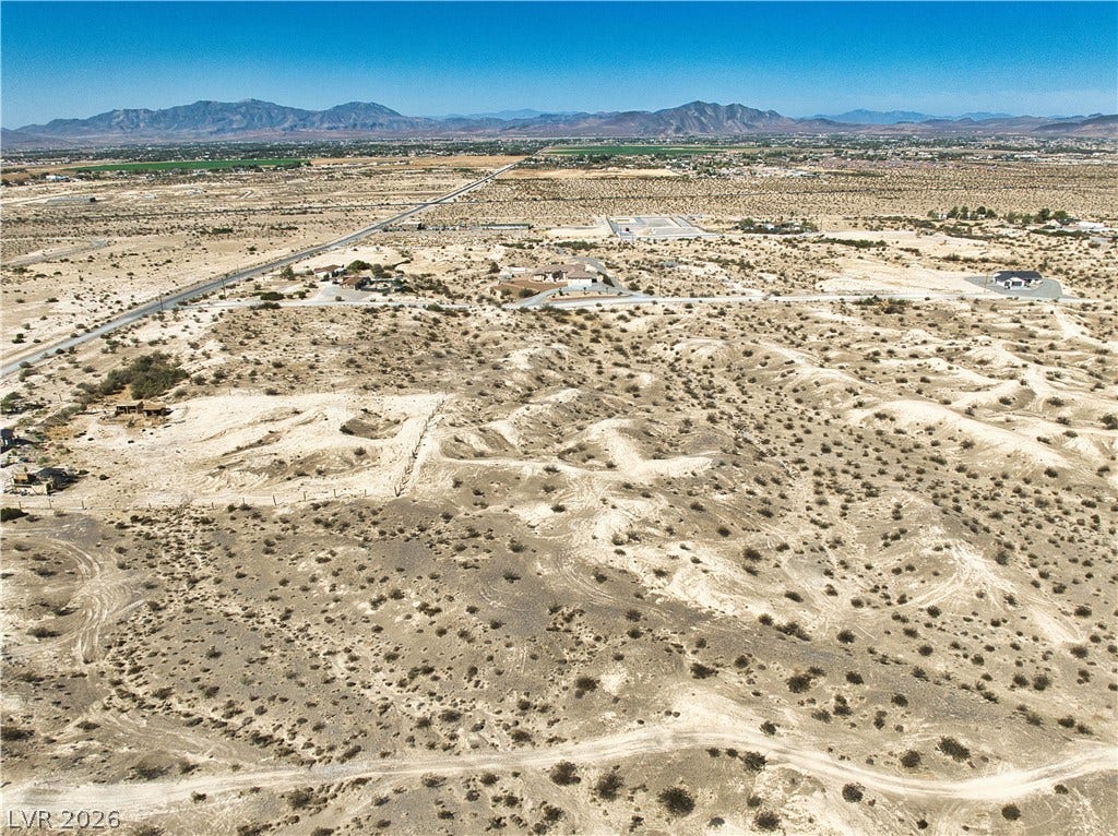 Vast desert terrain stretches toward a distant mountain range under clear blue skies.