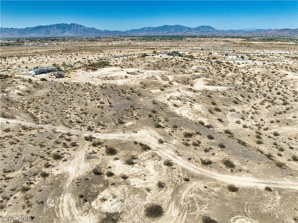 Rugged desert terrain stretches toward majestic mountain peaks under a clear blue sky.
