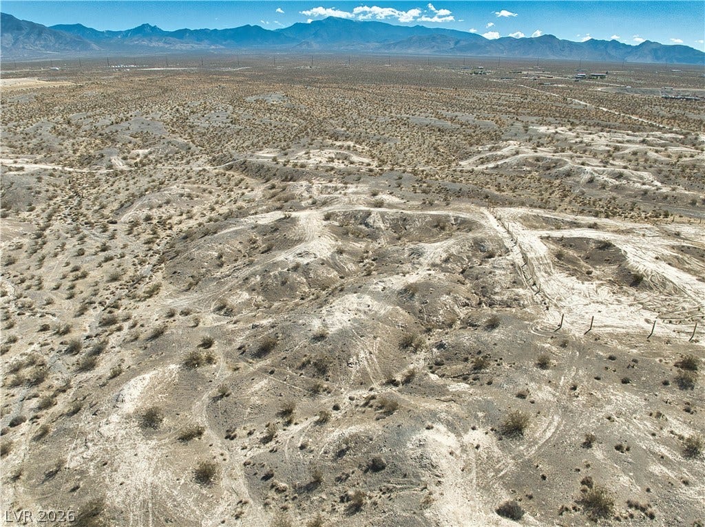 Rolling desert terrain stretches toward majestic mountain peaks under a clear blue sky.