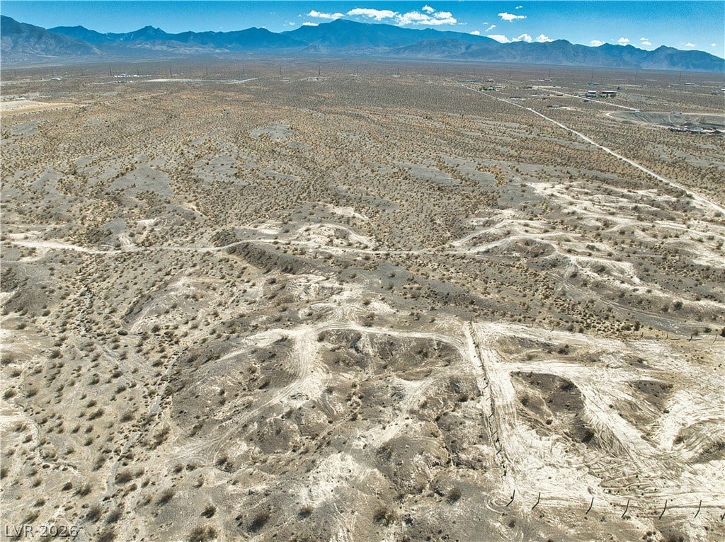 Dramatic mountain ranges frame the vast desert horizon under a clear sky.