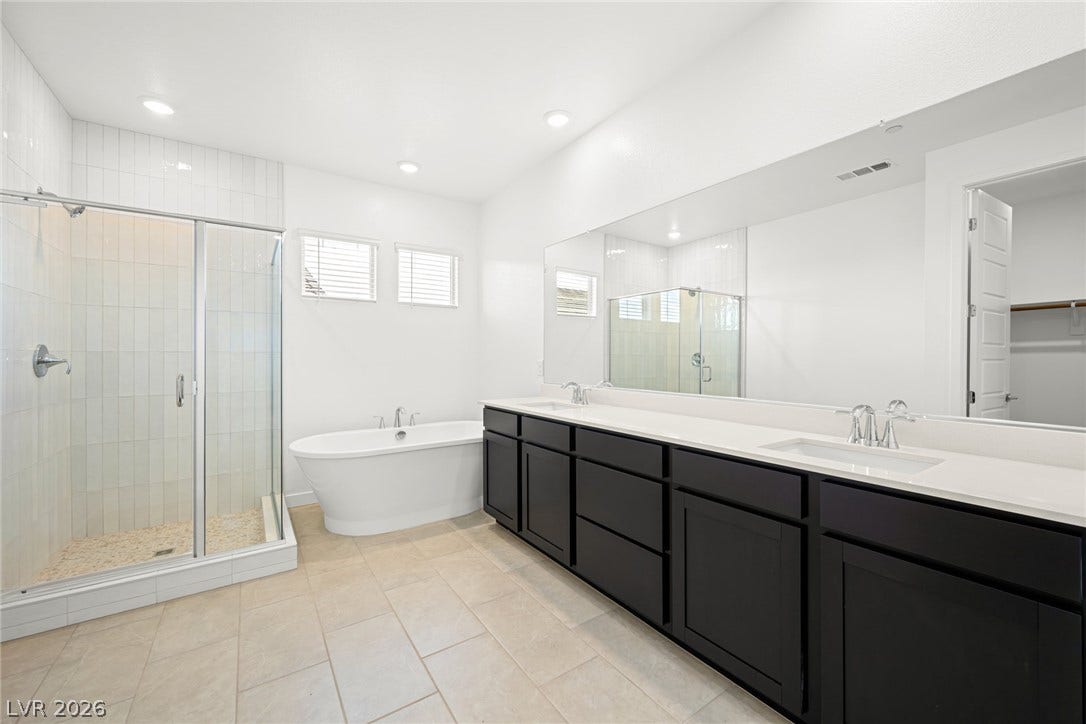 11823 Mimicking Song Lane, Las Vegas, NV 89138 A spacious double vanity and a freestanding soaking tub anchor this modern primary bathroom.